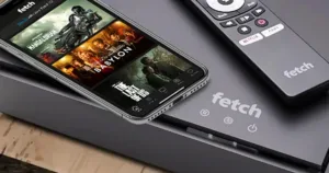 Photograph of a Fetch Mighty TV box with a Fetch remote and a smartphone running the Fetch app