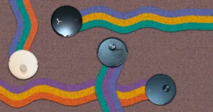 assortment of robot vacuums from above navigating a carpet