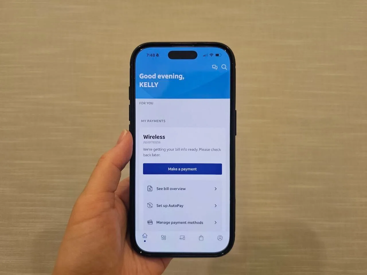 A hand holding a smartphone displaying the AT&T account app.