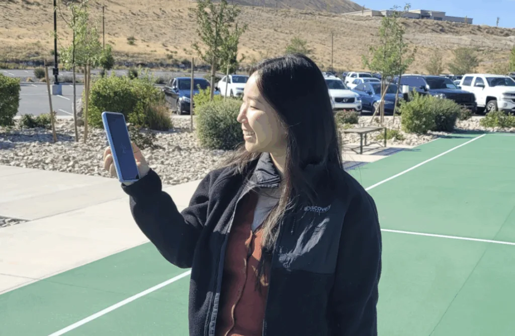 Reviews.org writer Kelly Huh holds her phone while standing outside