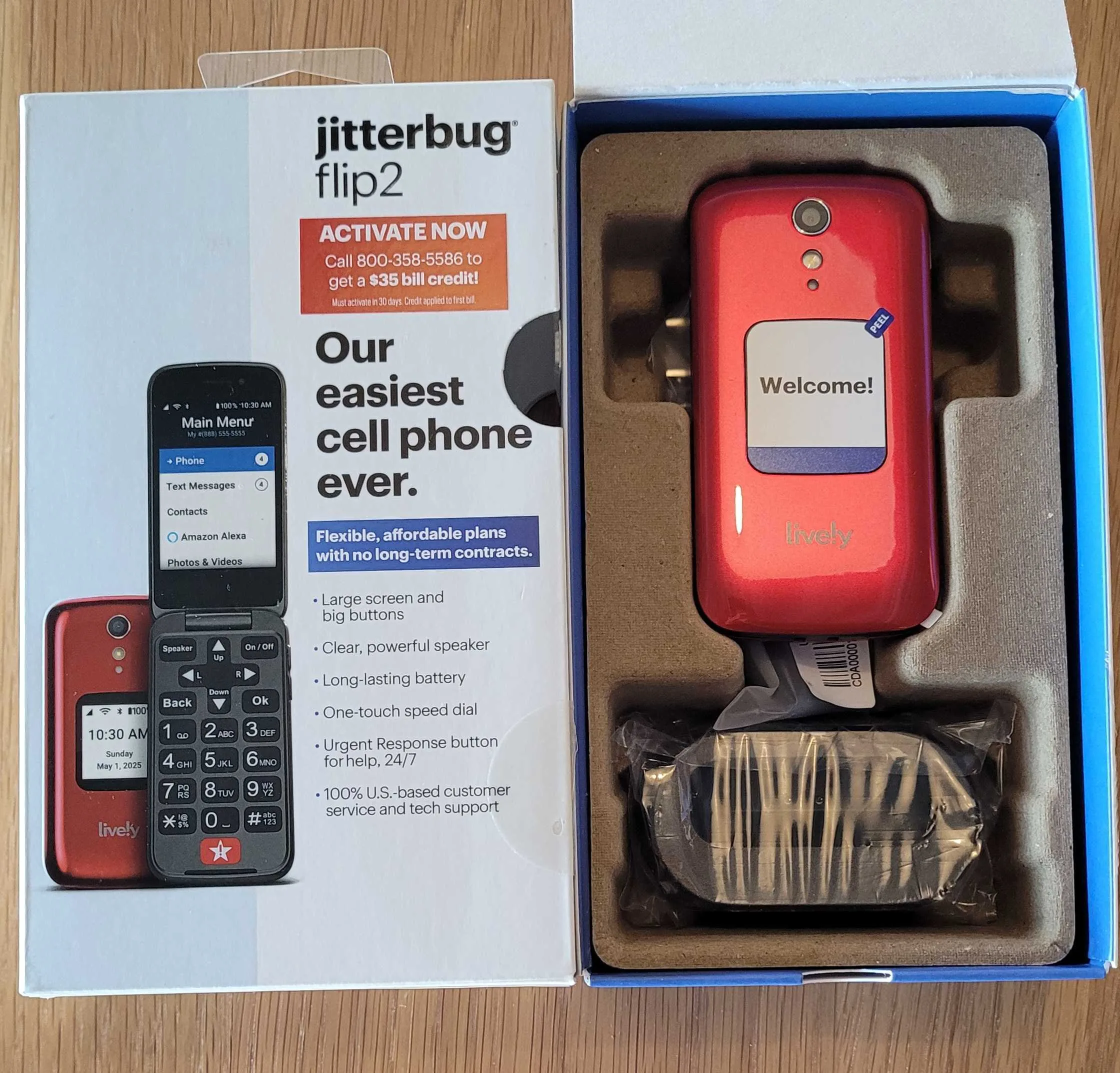 Red Jitterbug Flip2 phone in its open retail packaging next to its box. The box highlights ease of use with features like large buttons, a clear speaker, long-lasting battery, and a 24/7 Urgent Response button.