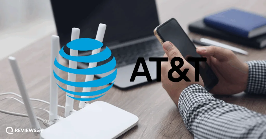 Person holding phone next to internet router. Image credit: IStock/ Liudmila Chernetska