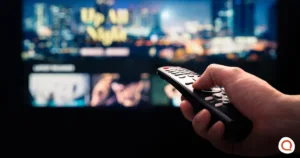 Person holding TV remote while browsing Netflix on screen considering canceling subscription after price increase