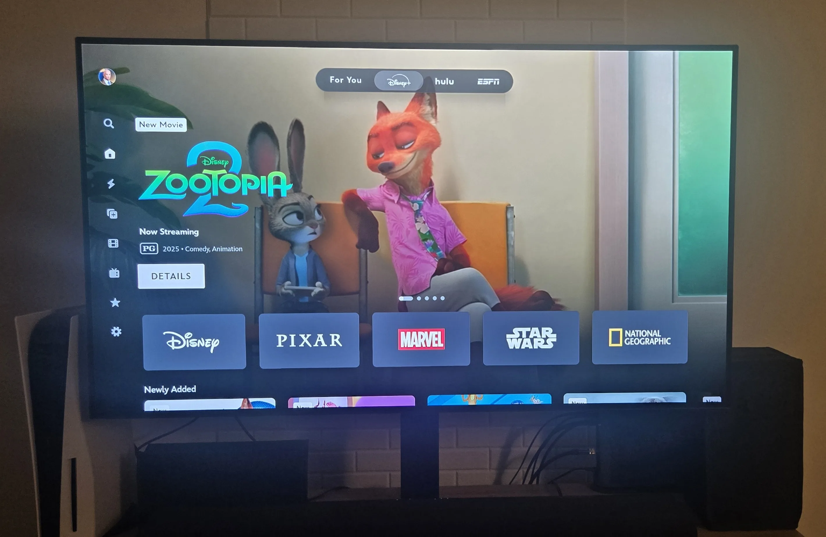 TV screen shows the homepage for Disney Plus. It features “Zootopia 2” along with five hubs for Disney, Pixar, Marvel, Star Wars, and National Geographic.