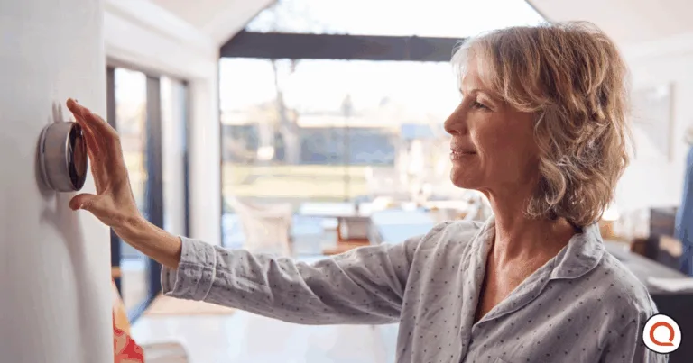 Woman adjusting smart home thermostat. Image credit: iStock/monkeybusinessimages