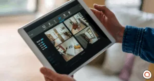 Person monitoring multiple home security camera feeds on a screen.