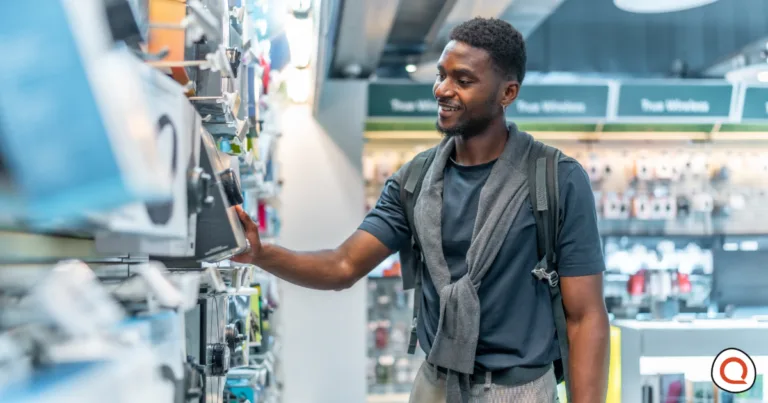 Man comparing smart home security devices on store shelf before buying a home security system