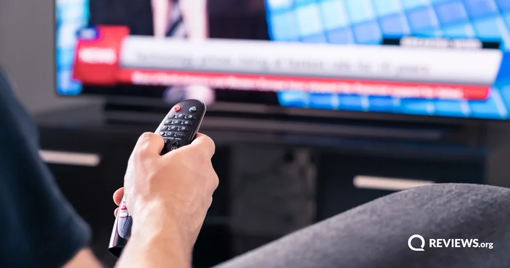 Person using TV remote to watch live news broadcast on television without cable.