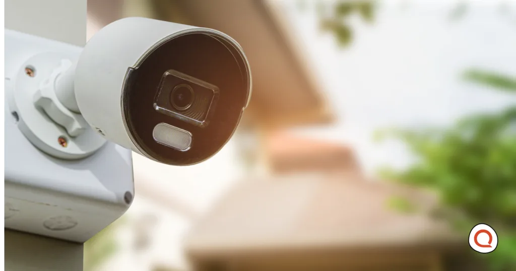 Outdoor bullet security camera mounted on a house exterior with a blurred residential background