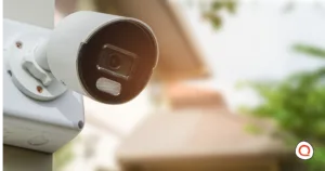 Outdoor bullet security camera mounted on a house exterior with a blurred residential background