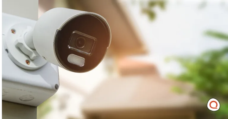Outdoor bullet security camera mounted on a house exterior with a blurred residential background