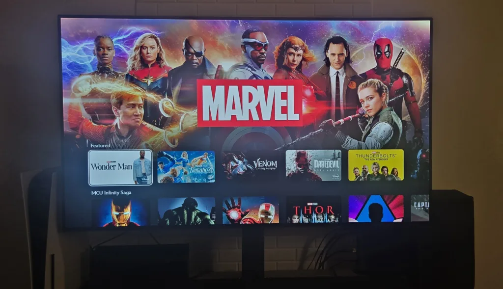 Disney+ Marvel hub on a TV screen showing featured titles including “Wonder Man,” “Fantastic Four,” “Venom,” “Daredevil Born Again,” and “Thunderbolts,” with MCU Infinity Saga films below.