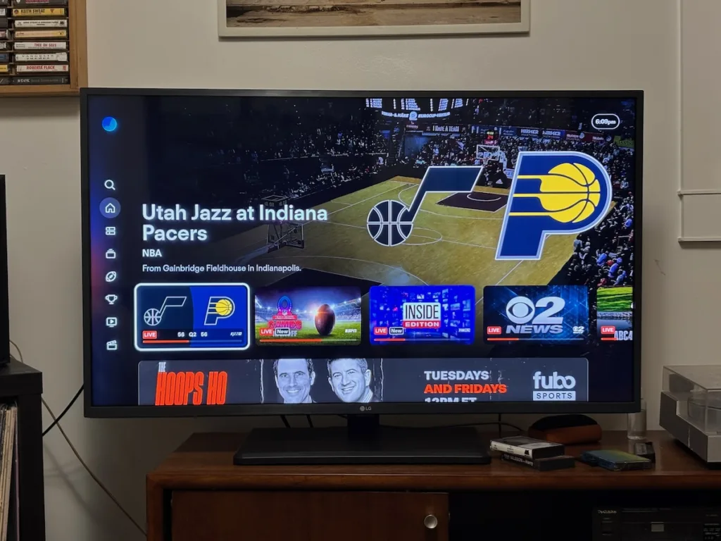 FuboTV home screen on a TV displaying the Utah Jazz at Indiana Pacers NBA game, with live sports and news channel tiles visible.