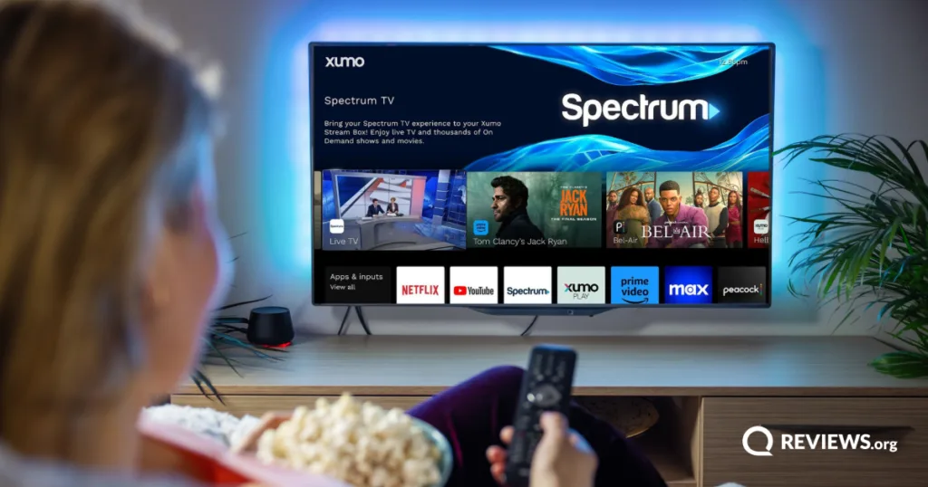 Woman watching Spectrum TV app on a Xumo Stream Box, with streaming options including Netflix, YouTube, and Prime Video displayed on screen