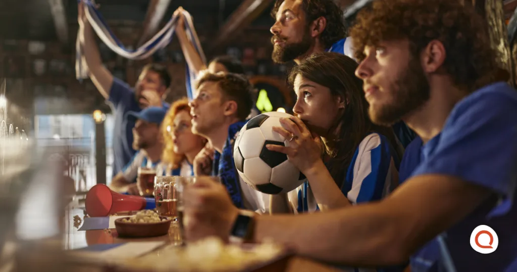 Soccer fans in blue and white jerseys watching the FIFA World Cup at a sports bar
