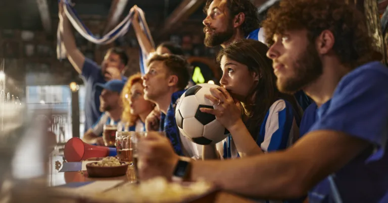 Soccer fans in blue and white jerseys watching the FIFA World Cup at a sports bar