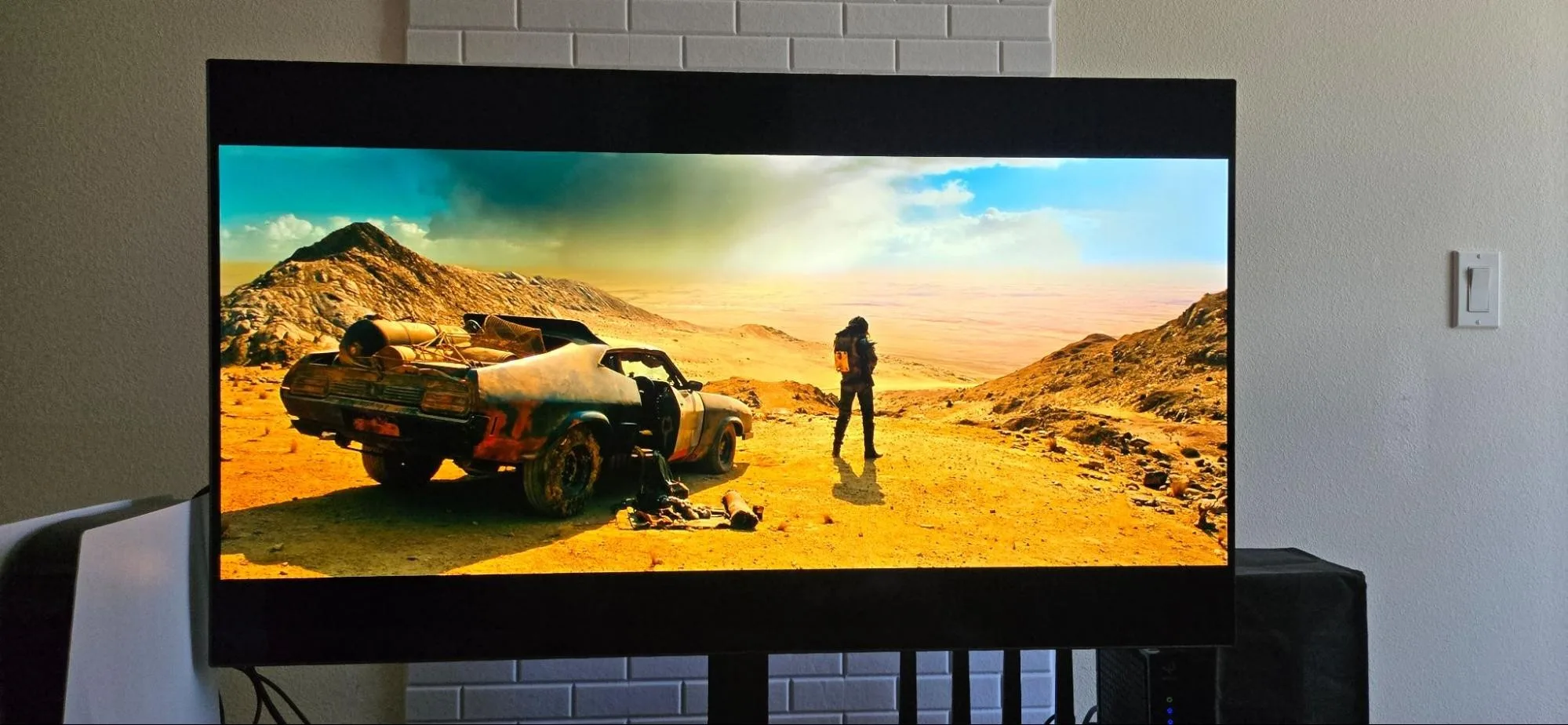 The image displays an LG TV with the opening shot of the film “Mad Max: Fury Road” in order to showcase the 4K HDR10+ and Dolby Vision with the Apple TV 4K device.