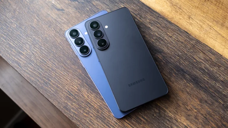 Reviewer using multiple smartphones, examining battery health and software settings on each device.