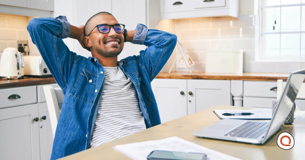 Man relaxing at his kitchen table with a laptop and phone, representing peace of mind that comes with reliable backup internet at home.