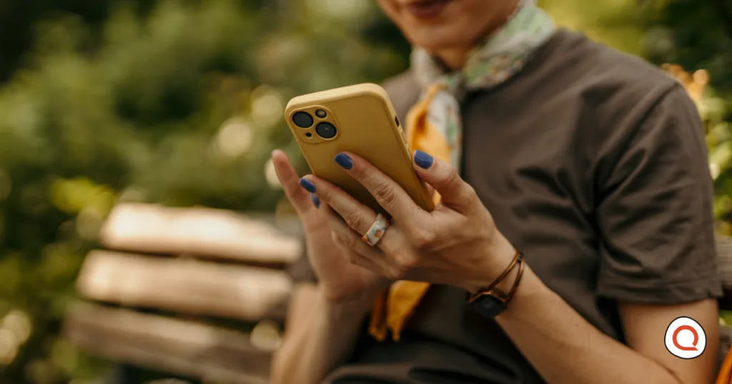 A woman checking her phone outdoors, holding on to her current device rather than rushing to upgrade to the newest model.