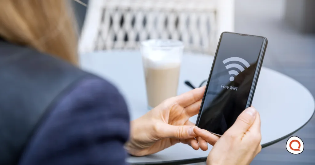 A woman connecting her phone to free public WiFi at a café, a common moment where incognito mode won't actually protect her privacy.