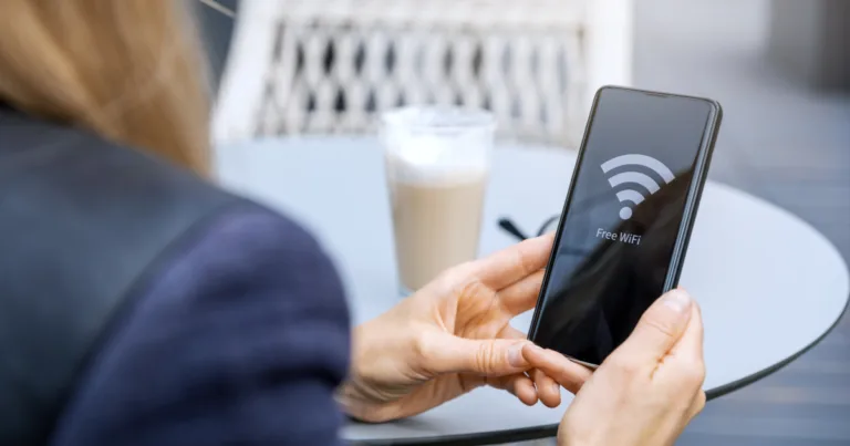 A woman connecting her phone to free public WiFi at a café, a common moment where incognito mode won't actually protect her privacy.