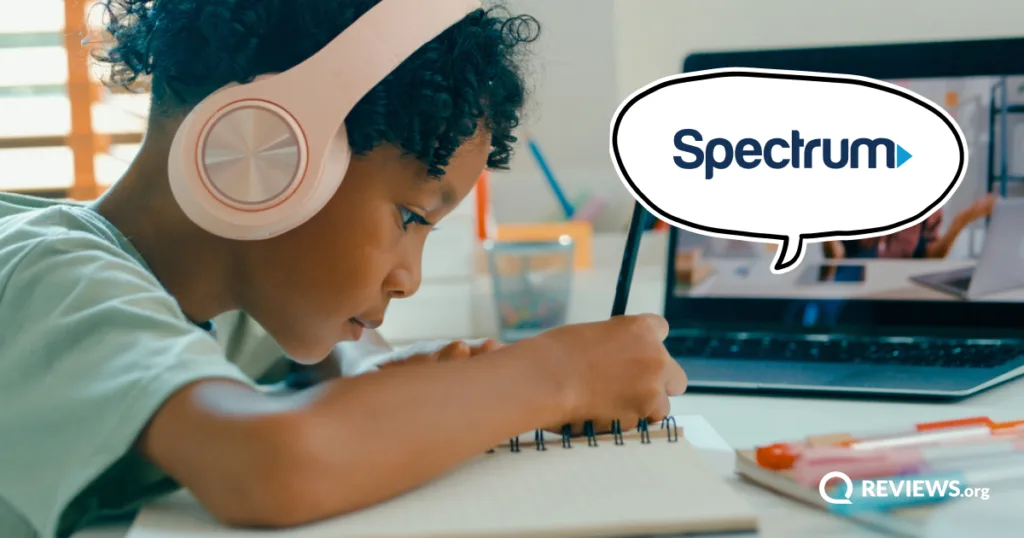 A student in headphones writes in a notebook beside a laptop video call, with a Spectrum speech bubble representing internet for online school.