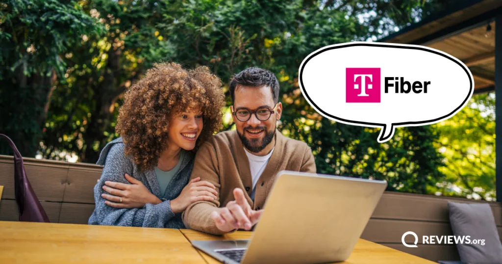 Two people sit outdoors with a laptop, comparing home internet plans, with a T-Mobile Fiber speech bubble.