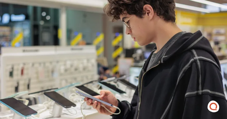 Young teenager examining a smartphone at a mobile phone retail store display, comparing different device options