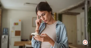 A woman looking concerned while checking her phone, wondering why her "unlimited" data plan has slowed down.