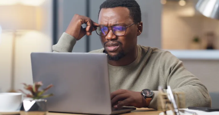 A confused man reviewing something on his laptop, questioning whether T-Mobile's new backup internet limits still work in his favor.