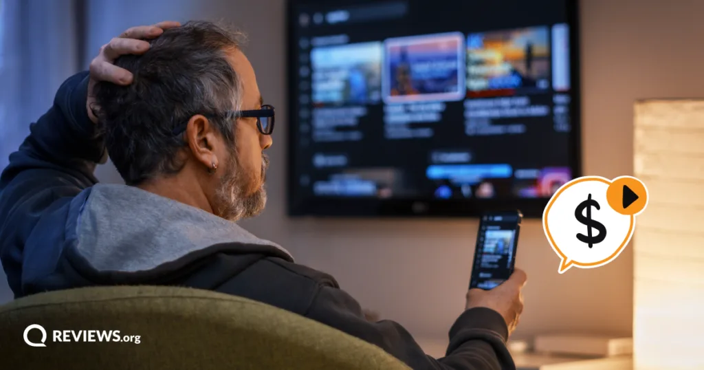 Man scratching his head while looking at his phone in front of a streaming menu, unsure whether to pay to share a family Hulu account.